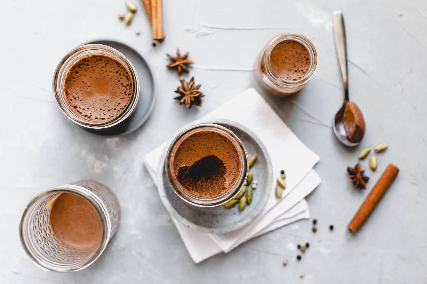 Schokomousse mit Lebkuchengewürz in Gläschen serviert und Sternanis sowie Cardamomkapseln und Zimtstangen dekoriert