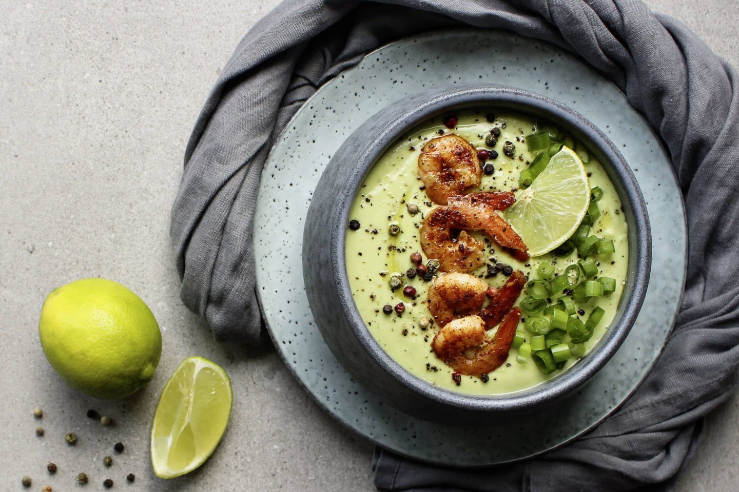 Avocadosuppe mit Veggy Hot+Spicy und Chili Garnelen in einer hellblauen Schüssel mit Limette und Jungzwiebel garniert