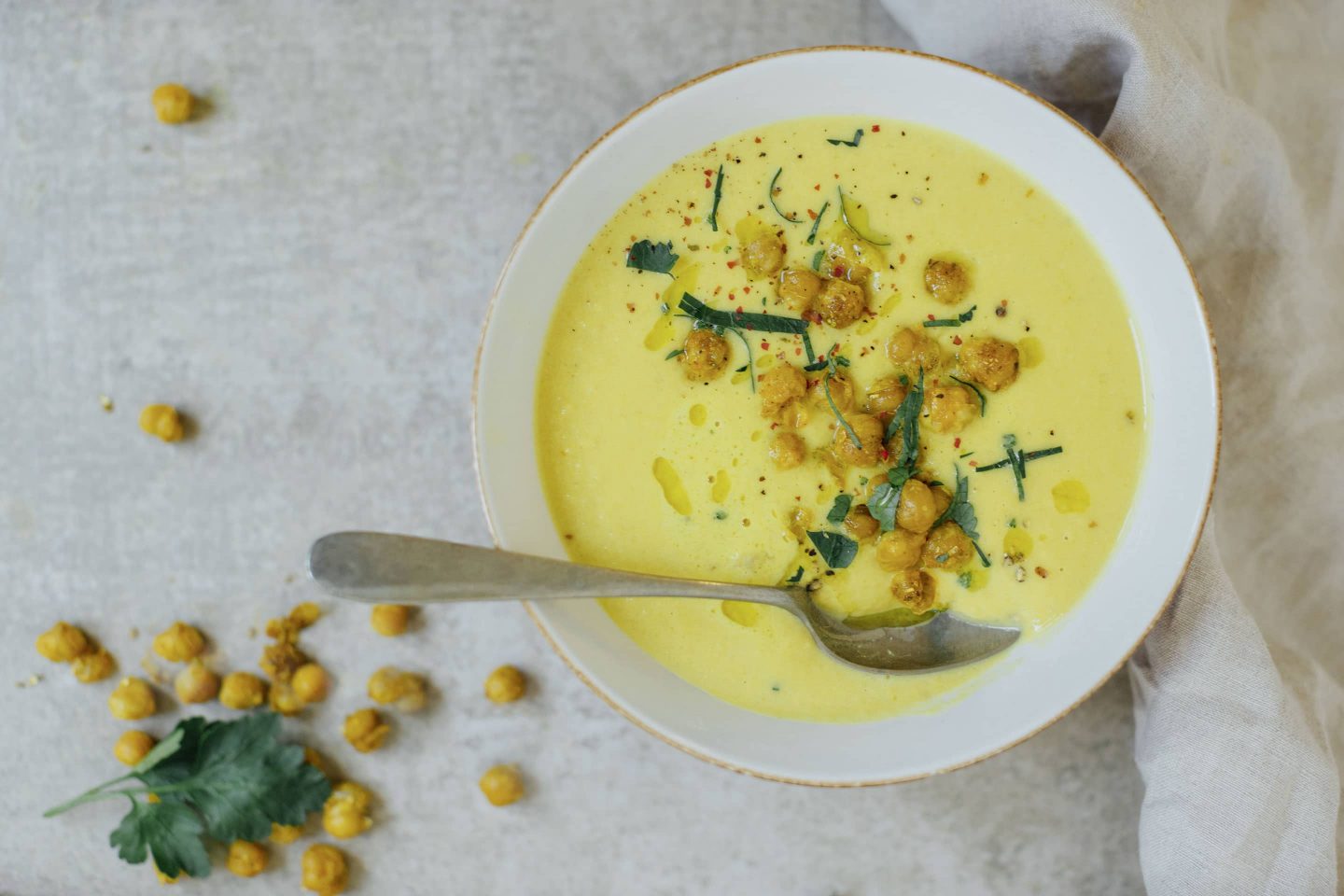 Kichererbsen-Suppe mit Curcuma, Koriander und Ingwer in einer weißen Schale mit Löffel