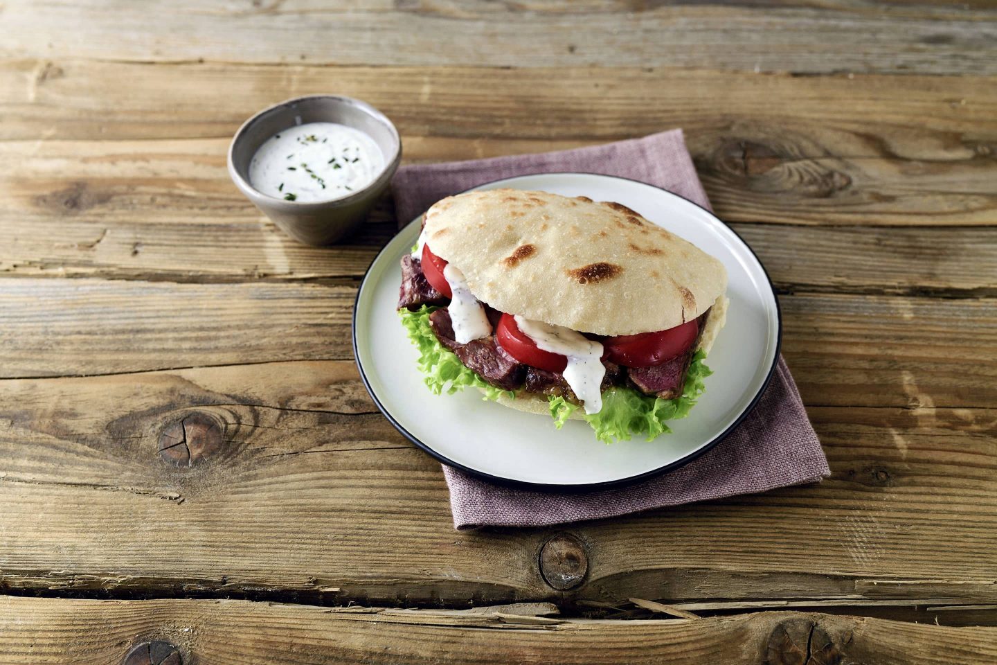 Pita Mit Rib-eye-Steak und Gemüse gefüllt auf einem weißen Teller angerichtet