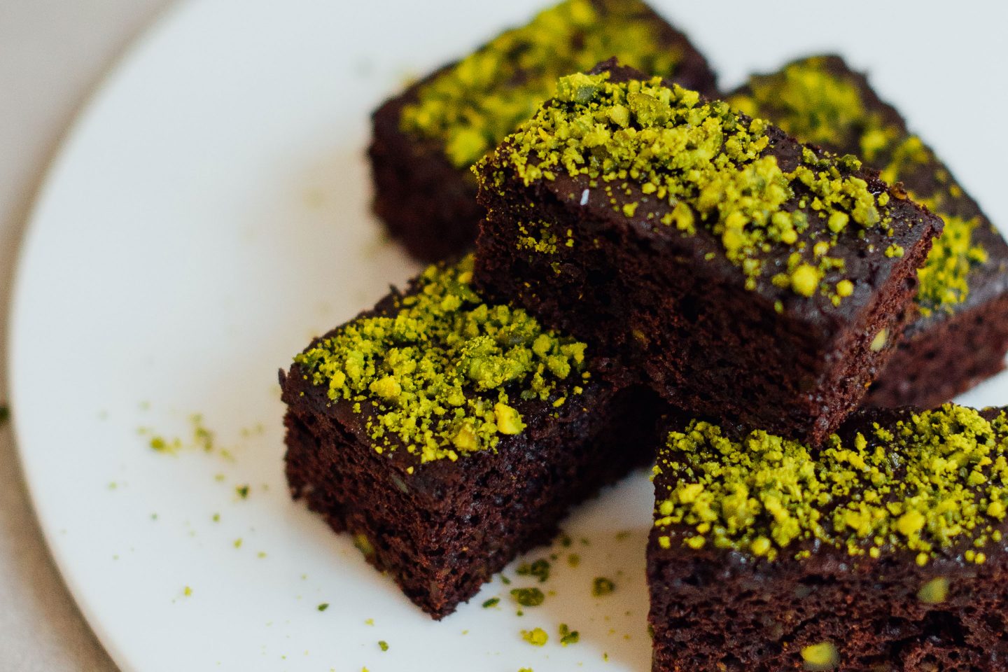 Low-Carb Schokokuchen mir zerstoßenen Pistazien getoppt auf einem weißen Teller