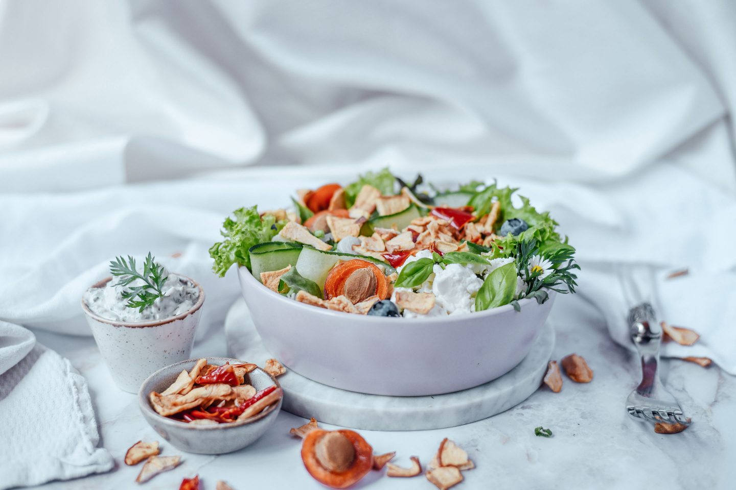 Salat mit Marillen und Heidelbeeren in einer Schüssel, Apfel Chips sind das Topping