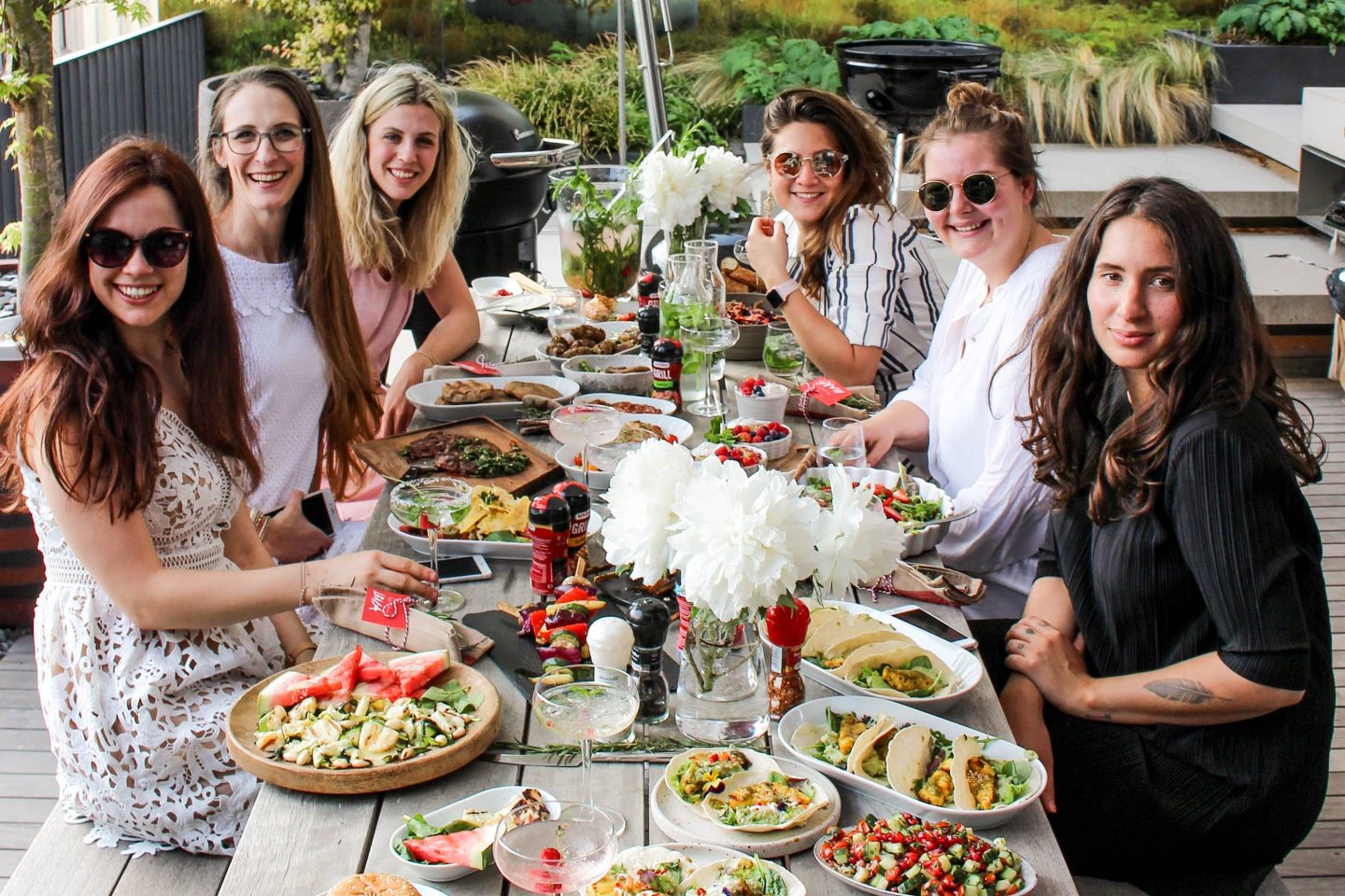 an einem Tisch sitzende Foodblogger mit ihren Gerichten