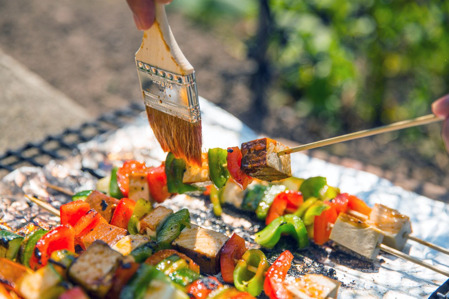 Tofu-/ Gemüsespieße werden mit einem Pinsel mariniert