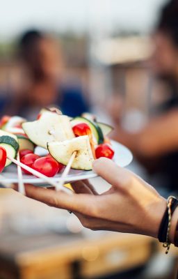 Frauenhand hält Teller mit veganen Grillspießen