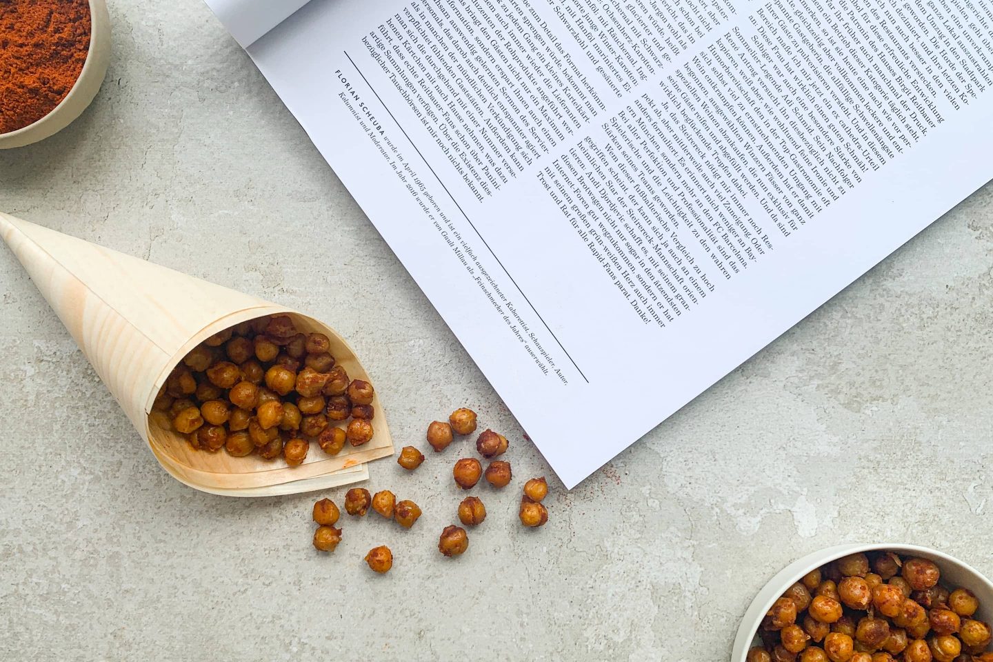 Gebackene Kichererbsen mit Cayennepfeffer in einer Schüssel und in einem Tütchen neben einem Magazin