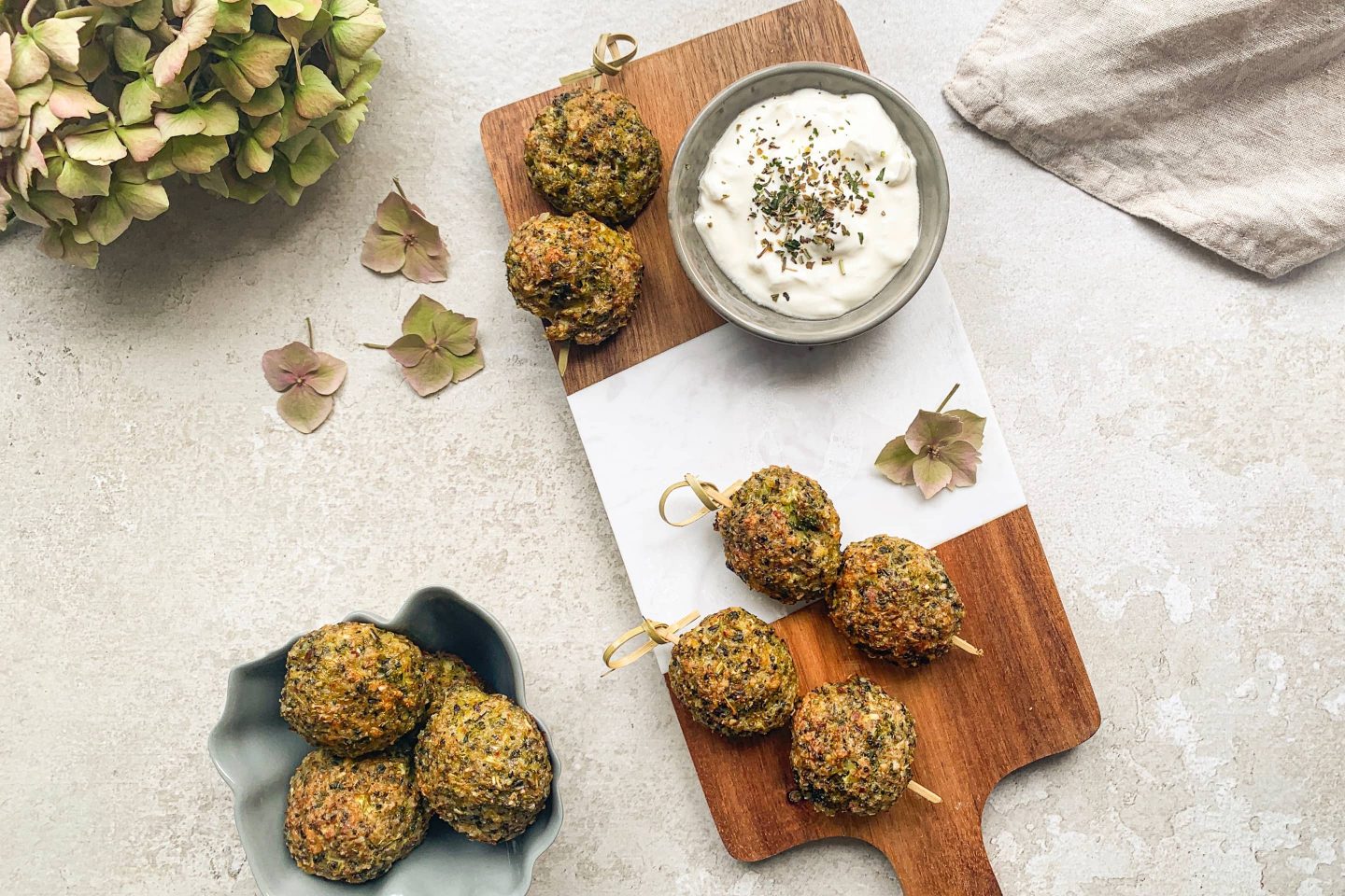 Broccoli Parmesan Balls auf einem Holzbrett mit Dip in einem Schälchen