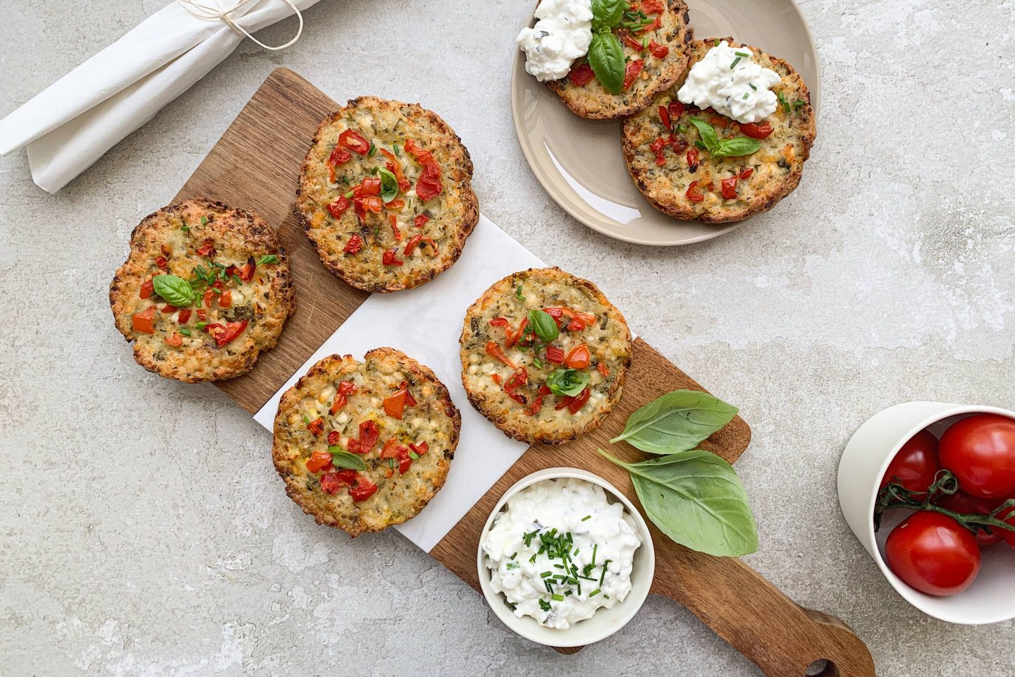 Cottage Cheese Cracker auf einem Holzbrett mit Tomate und einem Schälchen Cottage Cheese angerichtet