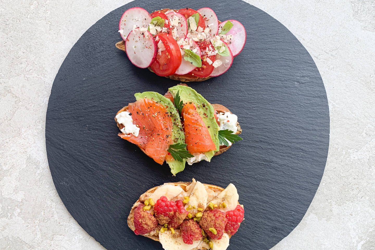 Süßkartoffel-Toasts mit dreierlei würzigen Toppings auf einer runden Schieferplatte