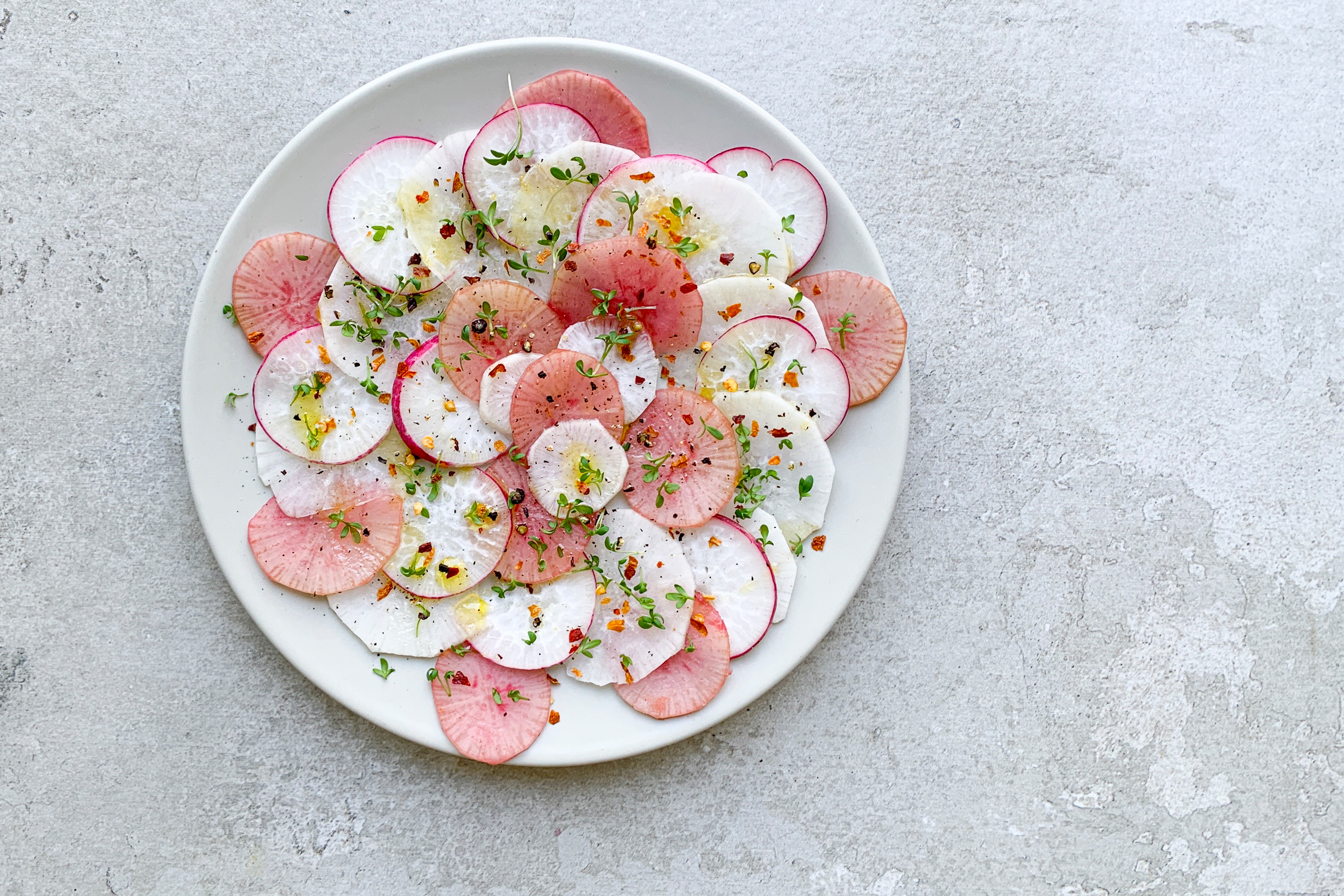 Buntes Rettich-Carpaccio auf einem weißen Teller