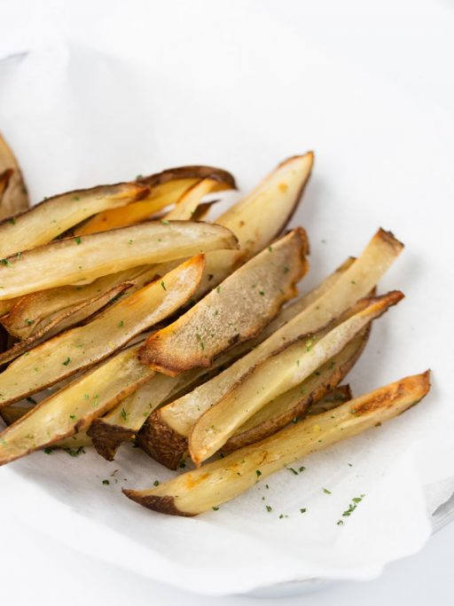 Ein Teller mit weißem Backpapier ausgelegt, darin befinden Sich Pommes