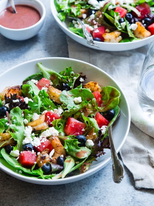 frischer, sommerlicher Salat mit Wassermelone, Shrimps und Feta in einem Tiefen weißen TEller auf hellem Untergrund