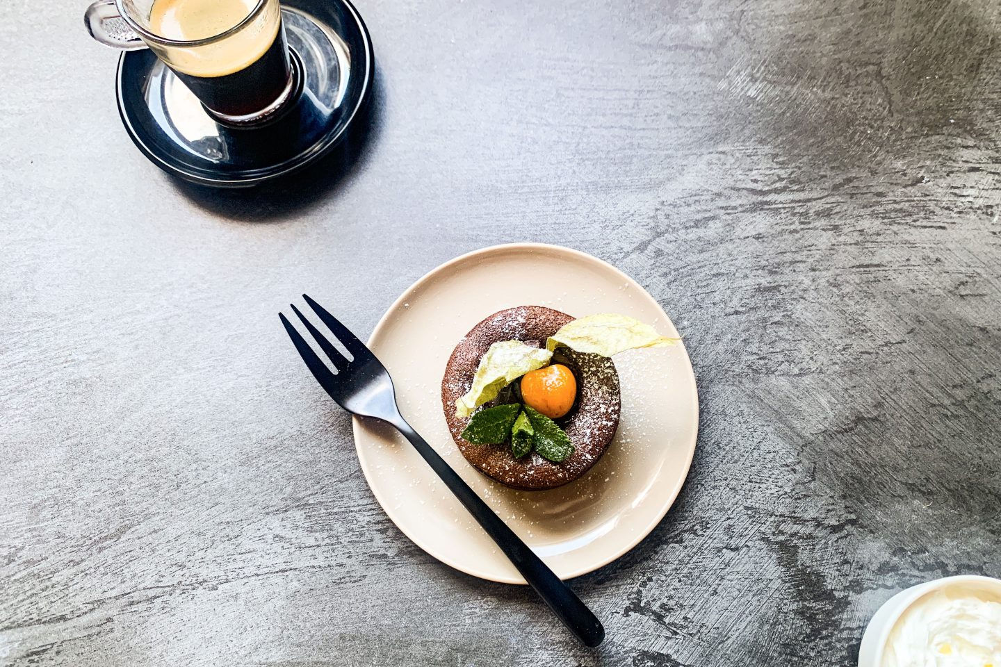 Spicey Schoko-Lava-Cake mit einer Physalis garniert auf einem hellen Teller