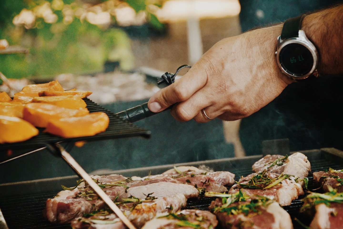 ein Mann Grillt und misst die Temperatur des Grillguts