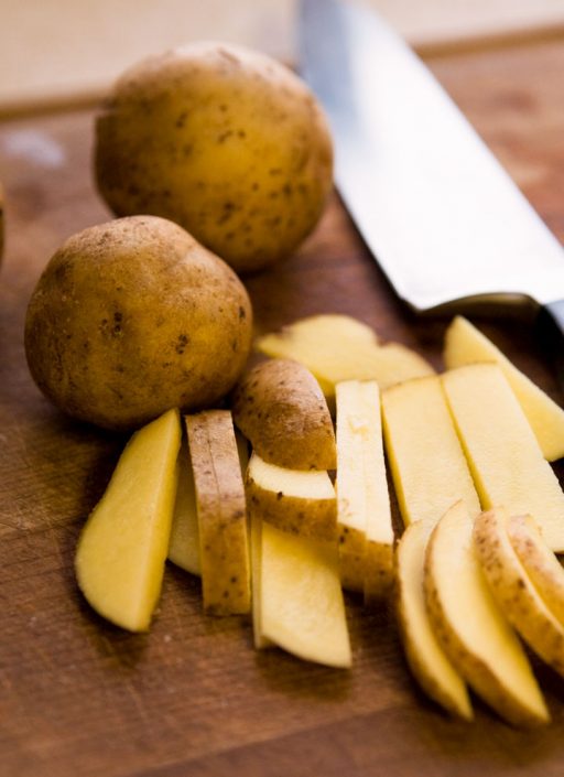 in Stifte geschnittene Kartoffeln mit einem Messer auf einem Brett