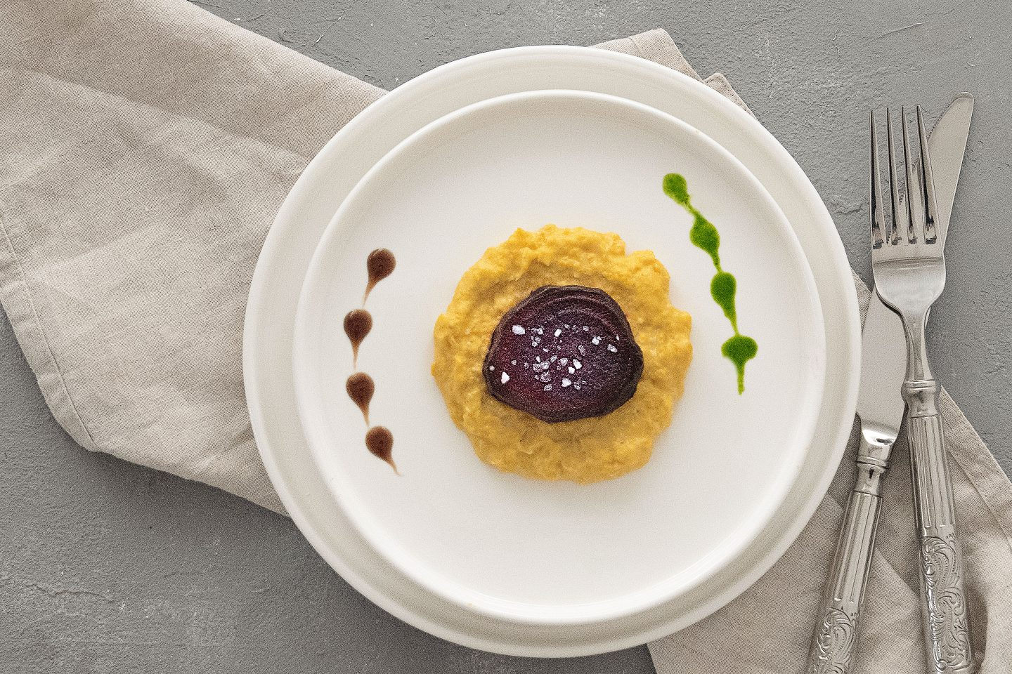 Rote Ruebe auf Maispüree mit etwas grüner Sauce und Balsamico Essig auf einem weißen Teller