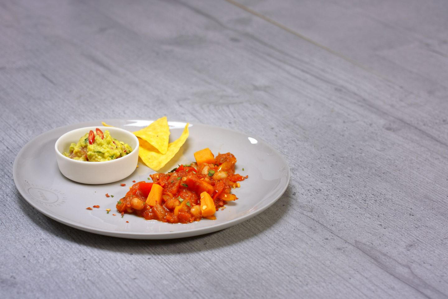 Chili Mit Suesskartoffeln und Guacamole in einem Schälchen sow Tortillachips