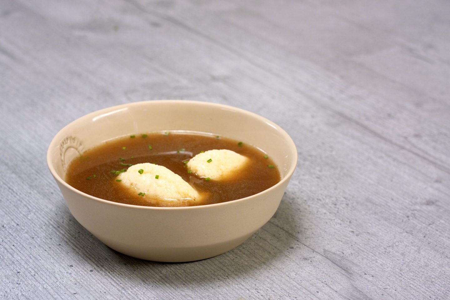 Rindsuppe mit 2 Grießnockerl in einer beigen Schale