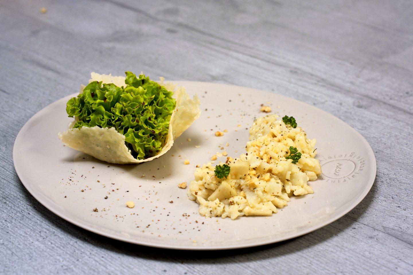 Topinambur Risotto mit Birne auf einem Teller mit Salat in einem Parmesanbecher