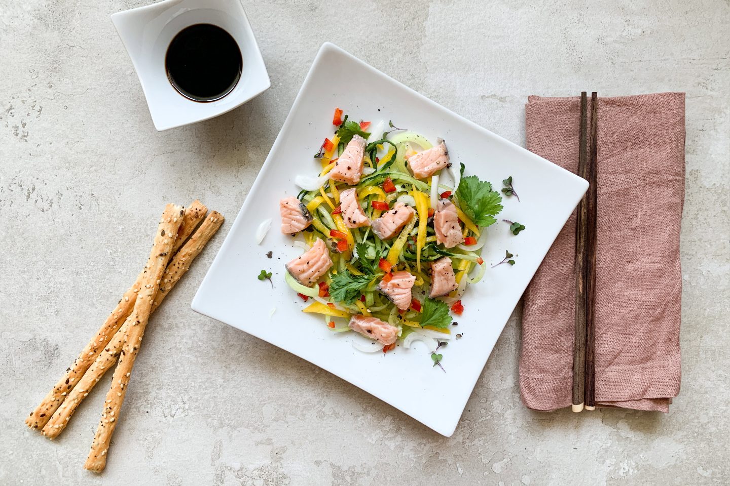 Lachs Ceviche auf einem eckigen weißen Teller mit Essstäbchen