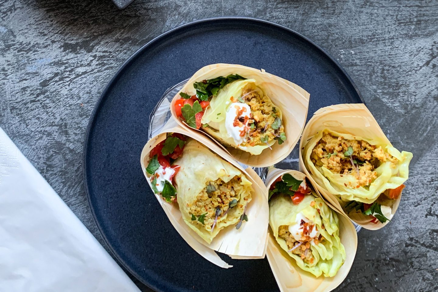 Curry Krautrouladen Burritos auf einem schwarzen Teller angerichtet mit Tomatensalsa und Sour Cream