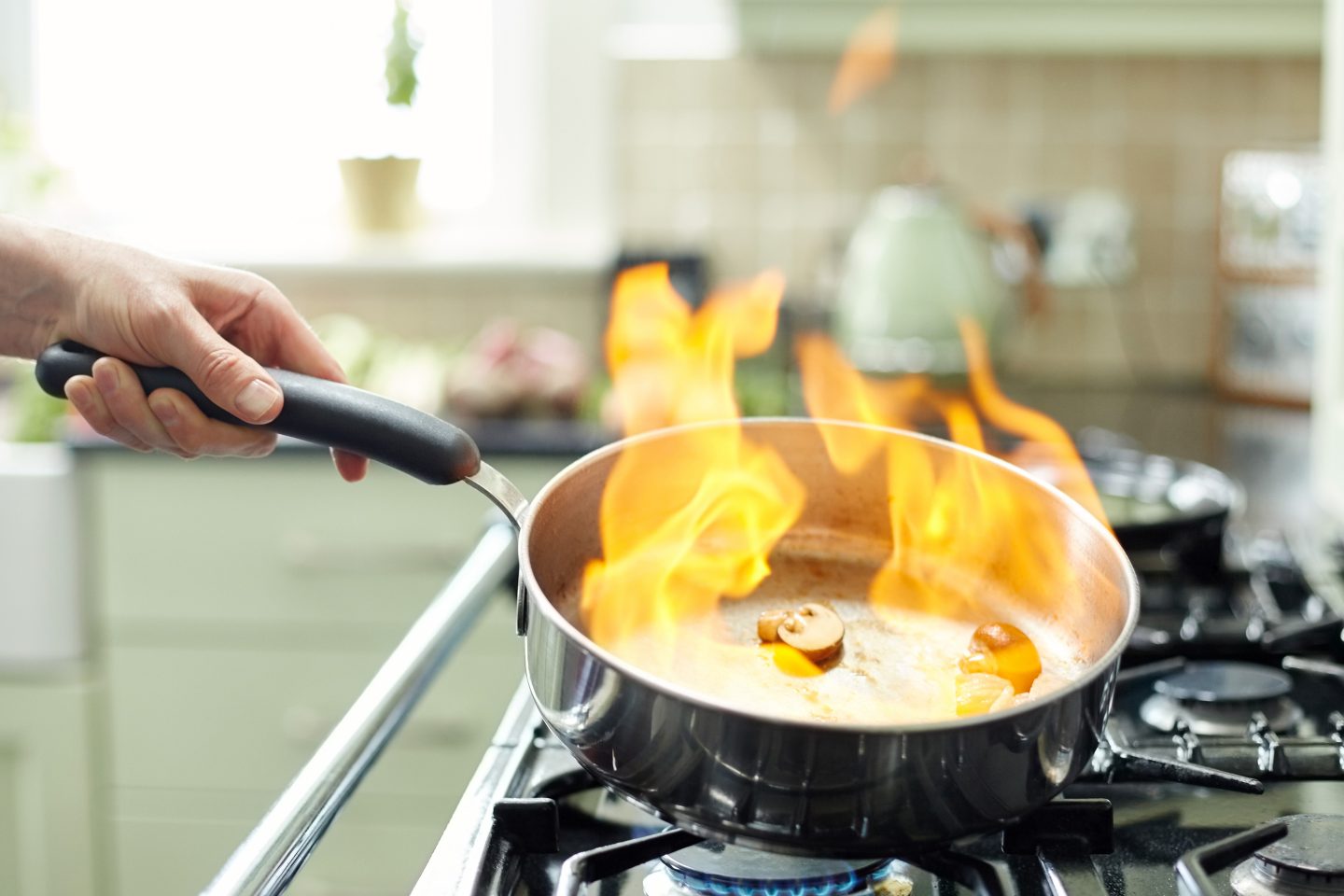 Pilze und Zwiebeln werden in einer Pfanne flambiert
