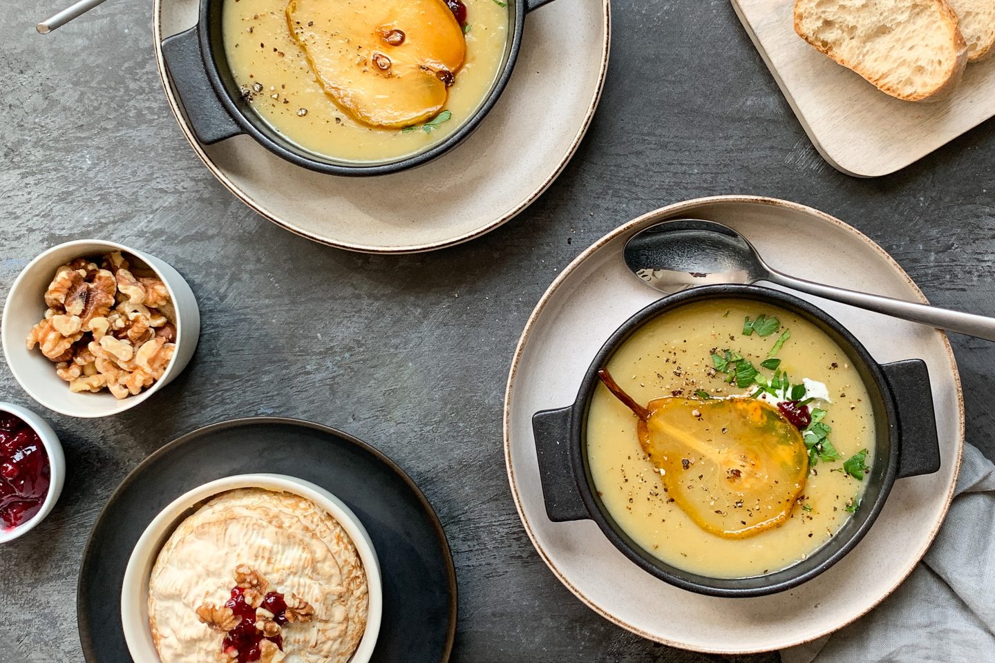 Lauch-Kartoffelsuppe mit Birne und Brie in dunklen Suppenschalen angerichtet