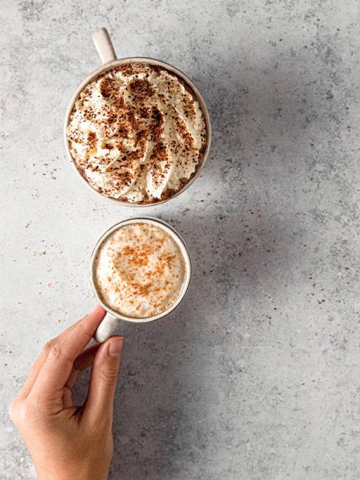 eine Hand hält einen Cappucchino mit Chai Moment