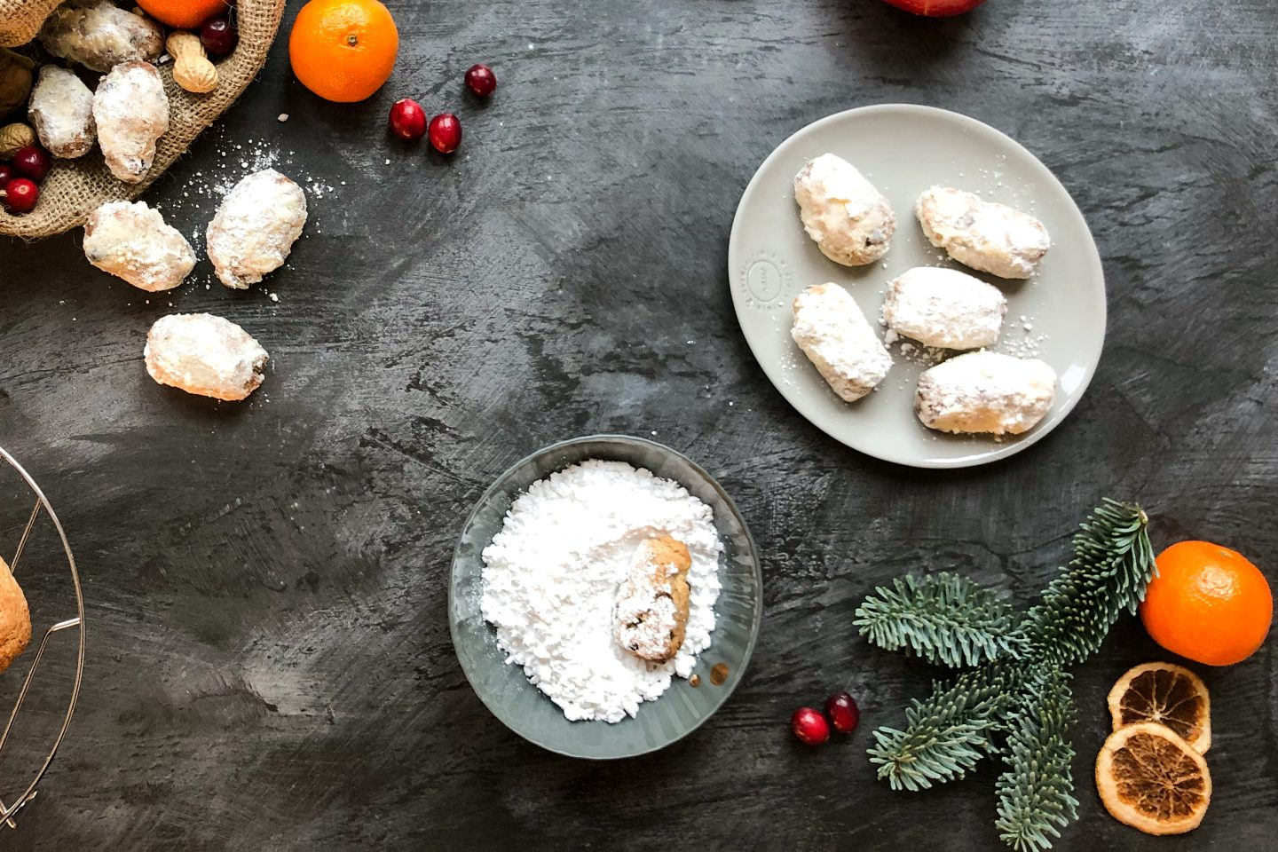 Mini Gewuerzstollen werden in Staubzucker gewälzt und liegen auf einem hellgrauen Teller
