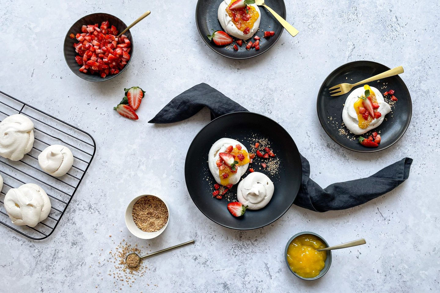 Schmackhafte Mini Pavlovas mit Lemon-Curd und Granatapfelkernen auf zwei Tellern