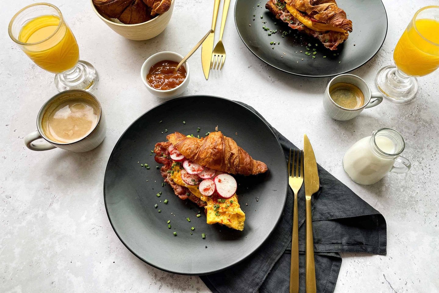 Ein Frühstückstisch mit pikant gefüllten Croissants, Kaffee und Orangensaft.
