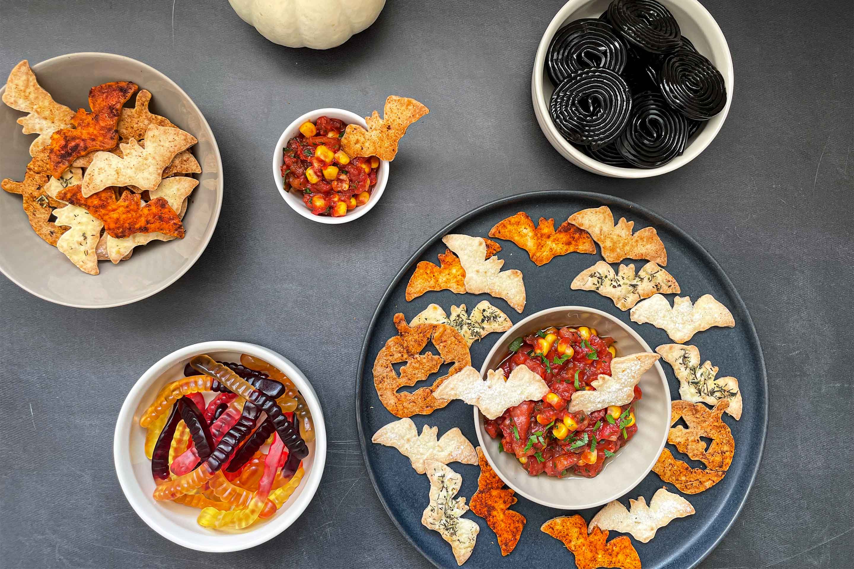 Spicy Halloween Chips mit rotem Tomatendip und zwei Schüsseln Süßigkeiten.