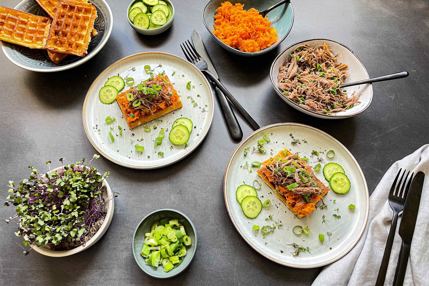 Pulled Goose und orientalischer Salat auf Waffeln mit Kresse und Gurkenscheiben.
