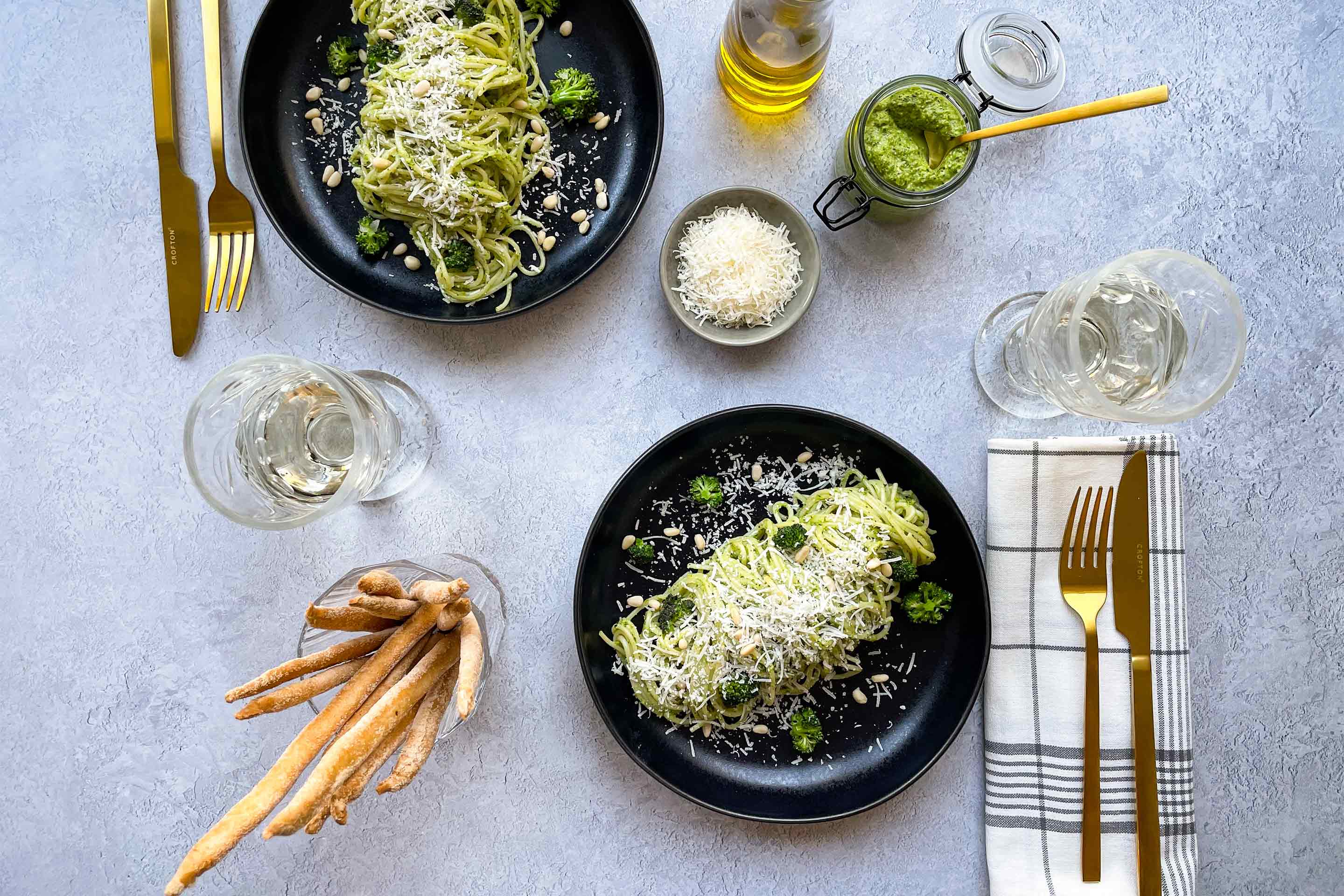 Zwei Teller Pasta mit Brokkoli-Bärlauch Pesto mit Parmesan, dazu Grissini.