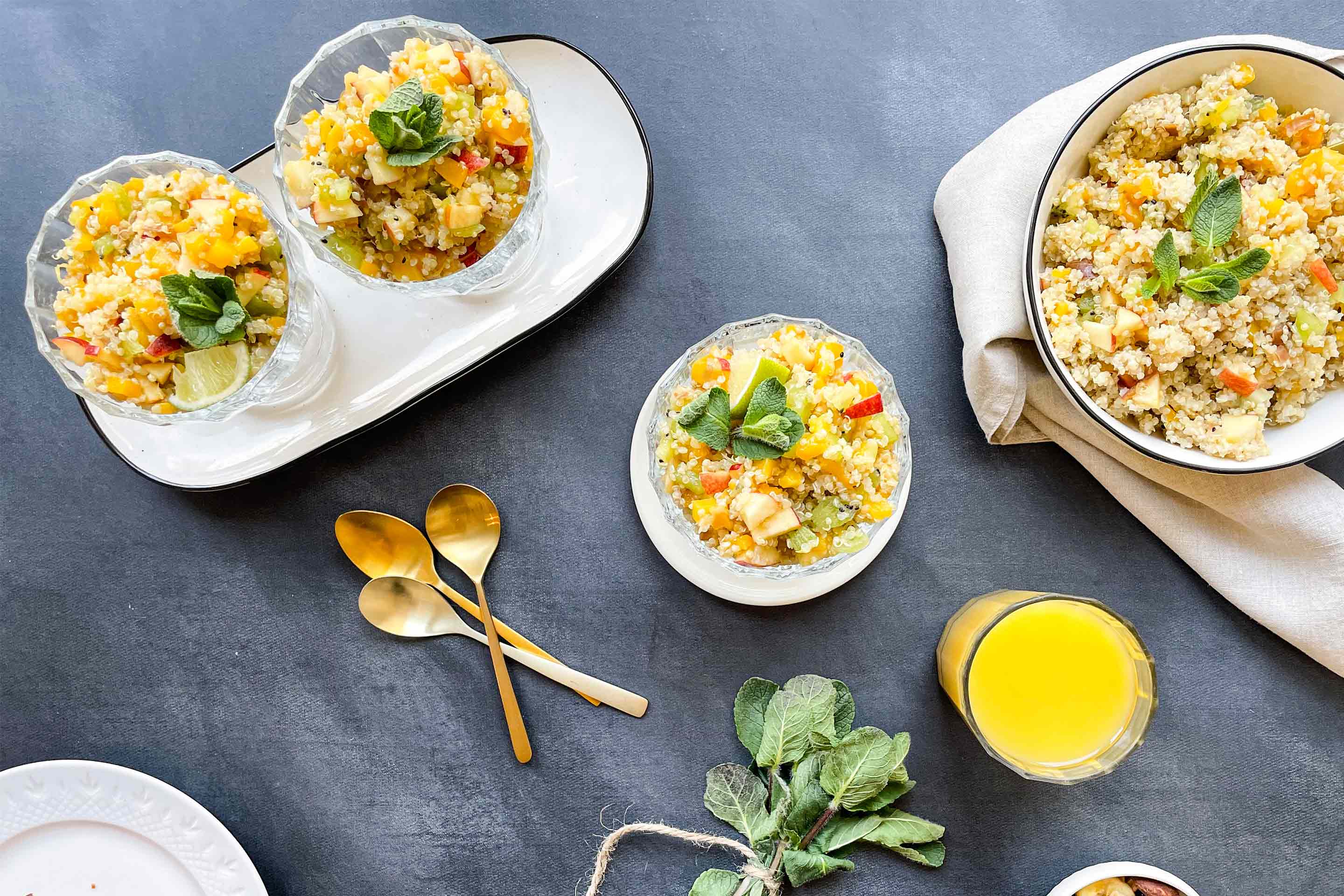 Fruchtiger Quinoa Salat mit Mango und Pfirsich mit einem Glas Orangensaft.